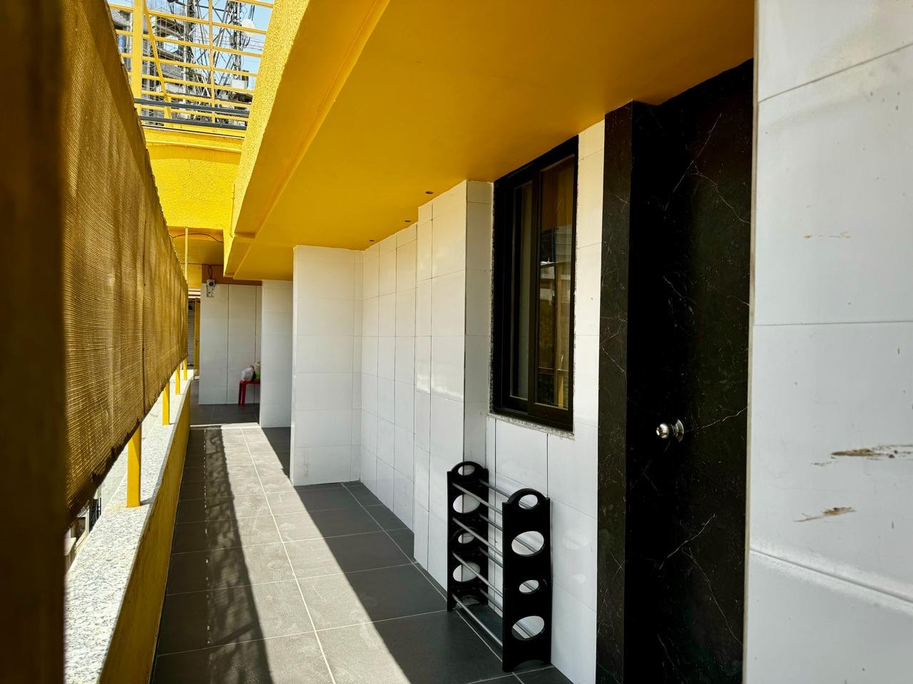 Bathroom with window, black door, and white tiled walls